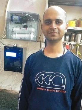 Individual standing proudly next to his Chanson Quality Water Purifier