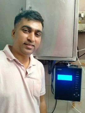 Individual with Chanson Quality Water Purifier demonstrating purified water